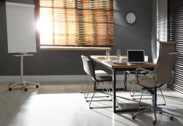 Stylish office interior with wooden table and flipchart
